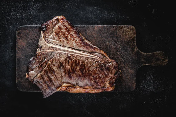Churrasco grelhado seco envelhecido carne T-bone bife na placa de corte rústico Imagens De Bancos De Imagens Sem Royalties