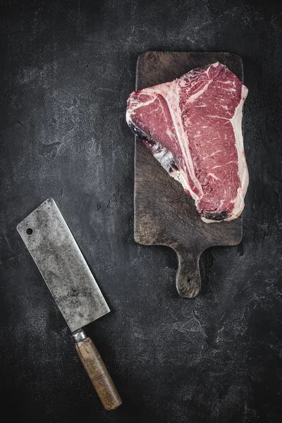 Dry aged beef raw t-bone steak on vintage cutting board Stockbild