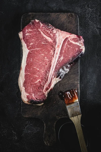 Hochwertiges, trocken gereiftes rohes T-Bone-Steak auf rustikalem Küchenbrett Stockfoto