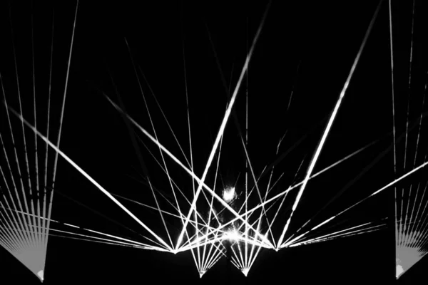 Parlak beyaz ışık huzmelerinin dinamik bir görüntüsü, merkezi bir noktadan dışarıya doğru, koyu siyah bir arkaplana doğru yayılıyor..
