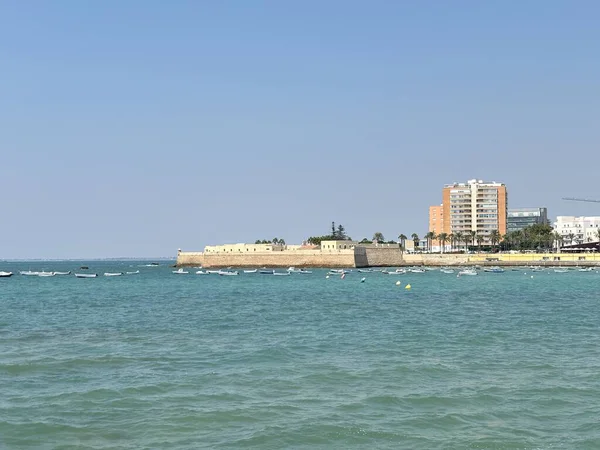 İspanya: Cdiz yakınlarındaki canlı Atlantik kıyı şeridi altın kumlar, tarihi kaleler, çarpan dalgalar ve yaz güneşi altında berrak mavi sular.