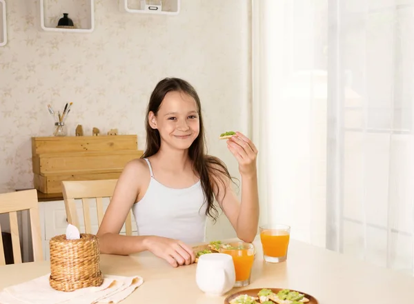 Linda Chica Preadolescente Sonriente Desayunando Sano Bocadillo Aguacate Jugo Naranja — Foto de Stock