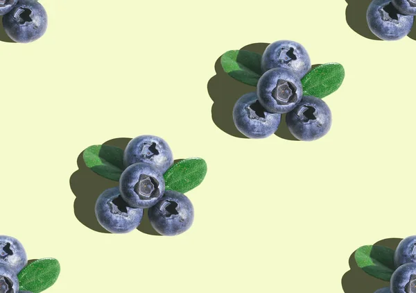 Blueberry with green leaves in hard light on colorful yellow background. Superfoods, diet seamless pattern. Vegetarian food