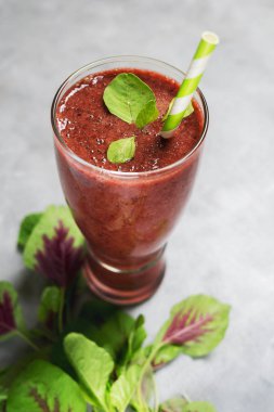 Kırmızı içecek yeşil ıspanak yaprakları ve parlak arka plan üzerinde uzun bardak Kağıt pipet ile. Superfoods, sağlıklı yaşam konsepti. Vejetaryen yiyecekler. Detoks. Metin alanı