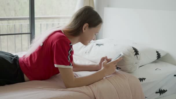 Bonito Teen Menina Com Rosa Cabelo Joga Telefone Cama — Vídeo de Stock