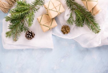 Düz manzaralı Noel ağacı dalları, oyuncaklar, köknar kozalakları ve mavi arka plandaki el sanatları kağıdında hediyeler. Yeni yıl tatili kavramı. Metin uzayı