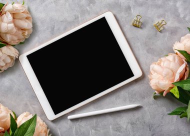 Düz görünüm modeli: Gri arkaplanda çiçekler ve kalemle dijital tablet. Metin uzayı 