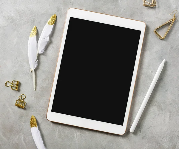 Düz görünüm modeli: Gri arka planda altın tüylü ve kurşun kalemli dijital tablet. Metin uzayı 