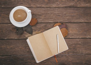 kahve ve sonbahar yaprakları ahşap arka planda defter ile
