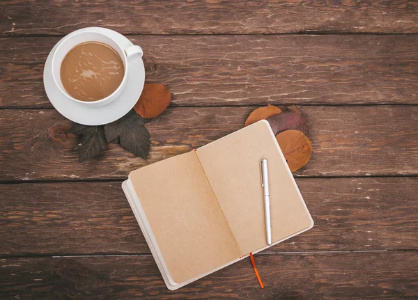 kahve ve sonbahar yaprakları ahşap arka planda defter ile