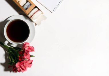 Bir kutu kurabiye, bir fincan kahve ve çiçek.