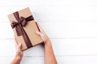 Beyaz ahşap arka planda hediyeyi tutan eller