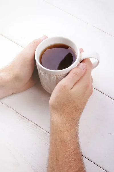 Αρσενικά Χέρια Κρατώντας Φλιτζάνι Ζεστό Τσάι Λευκό Ξύλινο Φόντο — Φωτογραφία Αρχείου