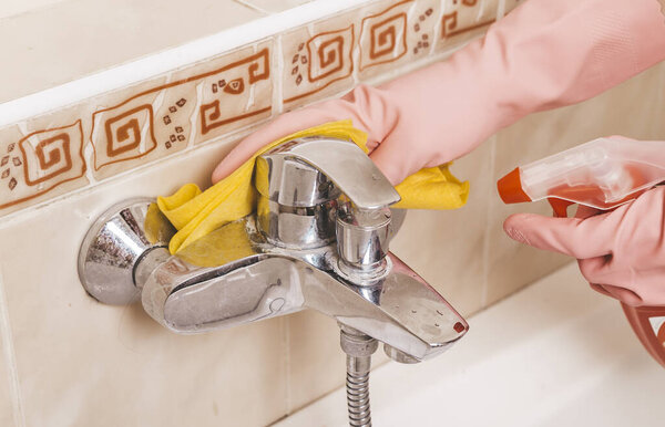 woman in rubbery gloves clean up bathroom with rag