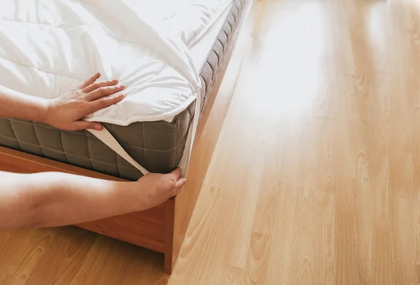 女性はベッドの上の寝具カバーかマットレスパッドを置くか またはクリーニングプロセスのために置くことである — ストック写真