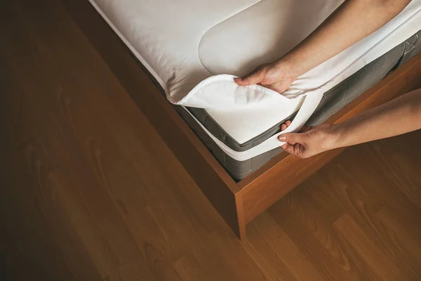 Woman is putting the bedding cover or mattress pad on the bed or putting off for cleaning process