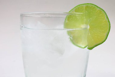 Buz küplü soğuk su bardağı ve kenarlarında limon dilimi. Tazeliğin, sağlıklı yaşam tarzının ve yaz içkilerinin mükemmel bir sembolü..