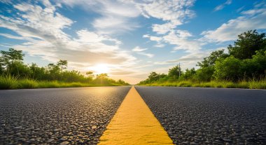 Yeşil ağaçlar ve parlak bir güneş tarafından çerçevelenmiş uzun bir yol ileri uzanıyor. Umut ve dinginlik mavi gökyüzü ve ilerlemeyi gösteren sarı çizgi tarafından uyandırılır..