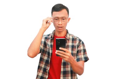 Asyalı bir adam elinde cep telefonu tutarken düşünceli bir ifade sergiliyor..