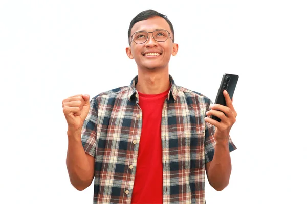 Asyalı bir adam iki eli havada bir cep telefonu tutuyor ve yüzü mutlu bir ifadeyle yukarı bakıyor..