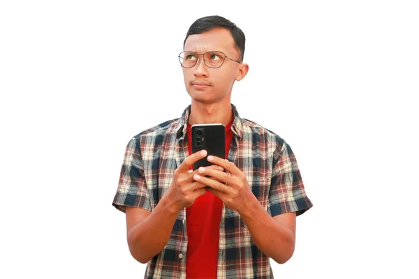 Asyalı bir adam elinde cep telefonu tutarken düşünceli bir ifade sergiliyor..