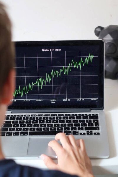 Person reviewing a fictional ETF chart on a laptop, hand on touchpad. Conceptual stock market illustration, not representing a real fund