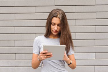 Şehirde bir tablet kullanan güzel siyah saçlı kadın. Kadının iş elbise