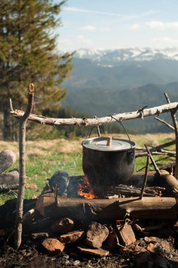 Eski bir küçük kazan yeşil dağ çayır dağların arasında bir ateşe ısıtılır