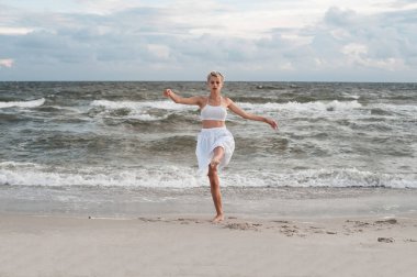 Genç güzel balerin dans ve deniz arka plan dışında poz.