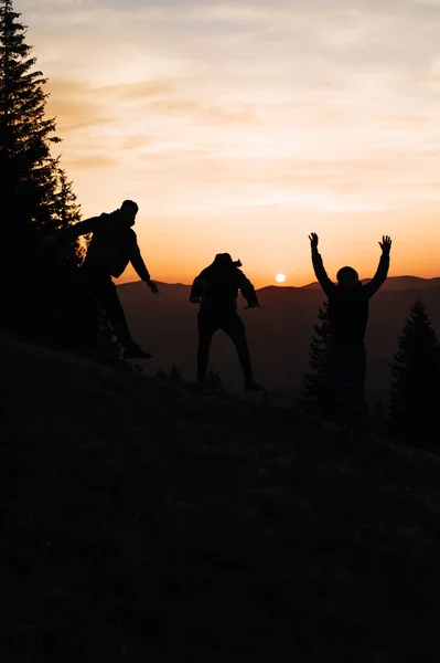 Morning sunrise in the mountains, silhouette of people who rejoice and jump