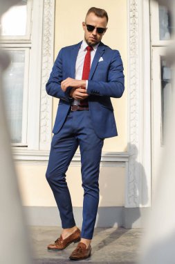 Son detay mükemmel. Yakışıklı genç işadamı duran kollarını ayarlama