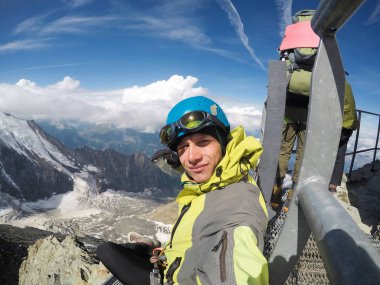 Genç dağcı üstüne oturdu ve dağların güzelliği hayran