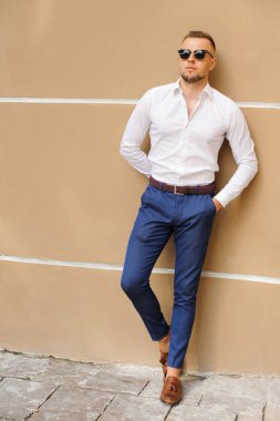 Burada bir göz atın! Beyazlı duran sarı arka plana karşı kendine güvenen genç yakışıklı adam giymiş