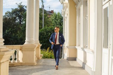 Genç yakışıklı işadamı portresi resmi kıyafet ve güneş gözlüğü duruyor. Kendinden emin ve başarılı erkek takım elbise.