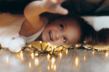 Yatağın altında mı saklanıyor ve bir oyuncak ve ışık ile oynayan bir kız