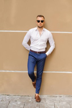 Burada bir göz atın! Beyazlı duran sarı arka plana karşı kendine güvenen genç yakışıklı adam giymiş