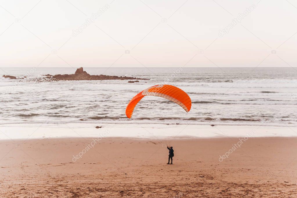 Paragliding on the beach. Sunset. Man landing on the beach near the ocean