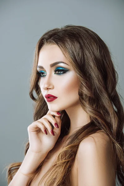 Brunette with expressive eye and lip makeup. Clean, radiant skin.