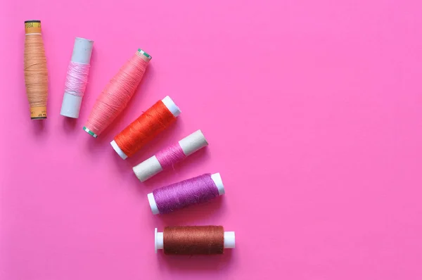 pembe iplik makaraları için pembe bir arka plan üzerinde dikiş. fotoğraf iş parçacığında. Pembe tonları konu. dikiş, dikiş, el yapımı. Kullanım için arka planlar, duvar kağıtları, afiş, reklam, kart