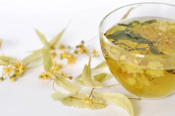 Fotoğraf şeffaf bir fincan bitkisel çay. çiçekler ve bitkilerin yaprakları. ıhlamur ve mürver, nane yaprakları çiçek. dinlenme zamanı. sıcak çay. kullanmak için arka plan, metin, tasarımınızın, kart