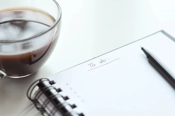 Yapılacaklar listesi not defterinde. Yapılacaklar listesi yazmak. beyaz sayfa, siyah kalem, bir fincan kahve. Bir gün planlama. etkinlik planlama. el ile yazma.