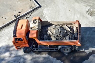 Heavy industrial dump truck .City road construction and renewal site. Dump truck brought in to repair roads and sidewalks, replacing curbs on the roads. Almaty, Kazakhsatn clipart