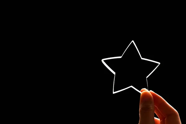 A woman gives a star. The concept of a positive rating, reviews and feedback on black background.