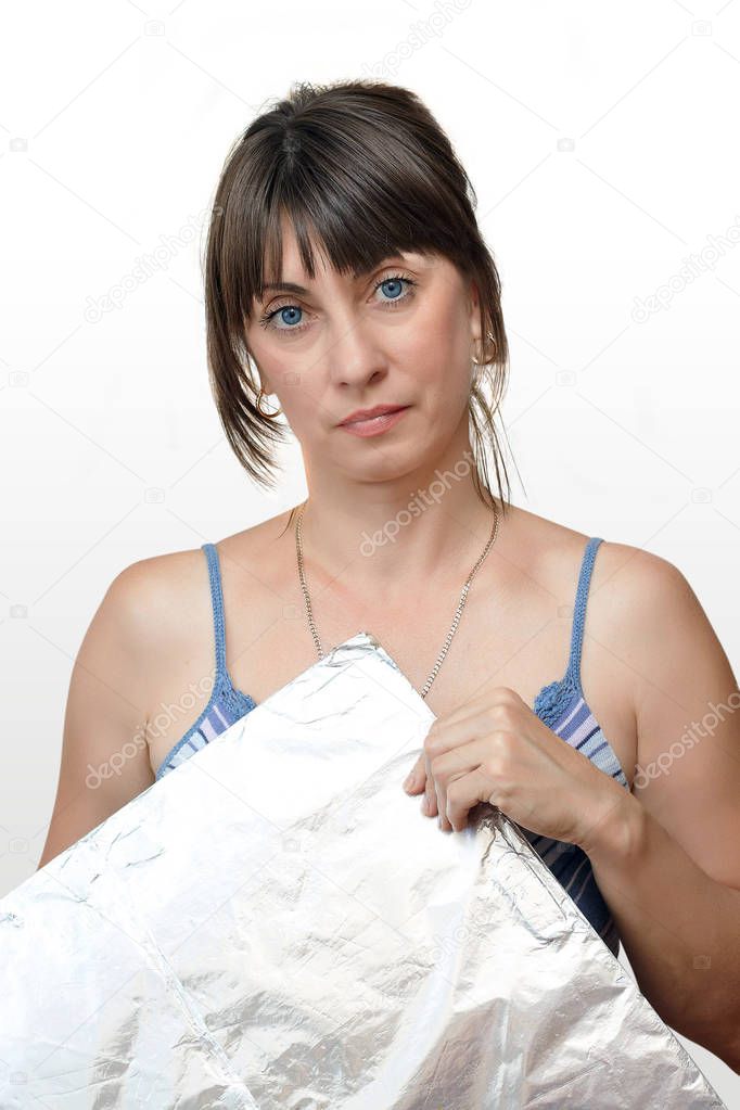 A woman holds a silver foil sheet on white background