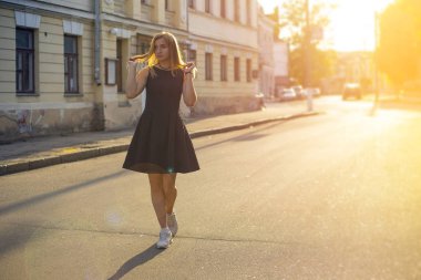Genç bir kadın yürür vintagestreet güneş ışığı dolu. Geniş görüş.