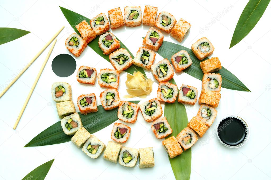 Japanese food. Advertising composition with rolls, ginger and chopsticks on the white background.