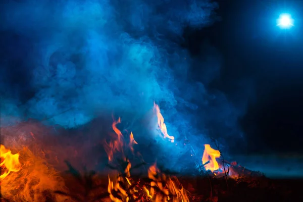 夜の焚き火の炎の上に青い色の煙 — ストック写真
