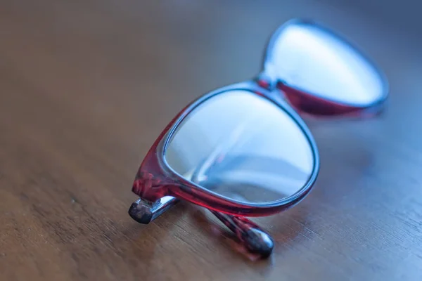 Eyeglasses in plastic frame on  wooden surface. Close up view.