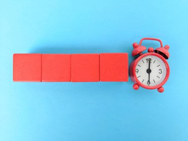 Dört kırmızı bloktan oluşan canlı bir kompozisyon, mavi bir zemin üzerinde kırmızı bir retro çalar saatin yanında dizilmiş, zaman aktarımı, renk kontrastı ve oyuncu tasarım fikirleri