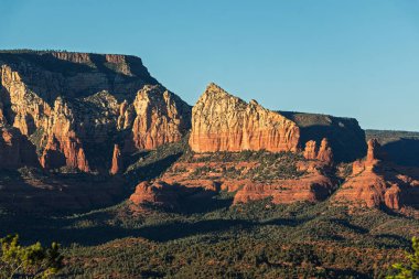 Sedona, Arizona, ABD 'de mavi gökyüzü altında geniş bir dağ silsilesi. Mavi gökyüzü altında tüylü beyaz bulutlar.